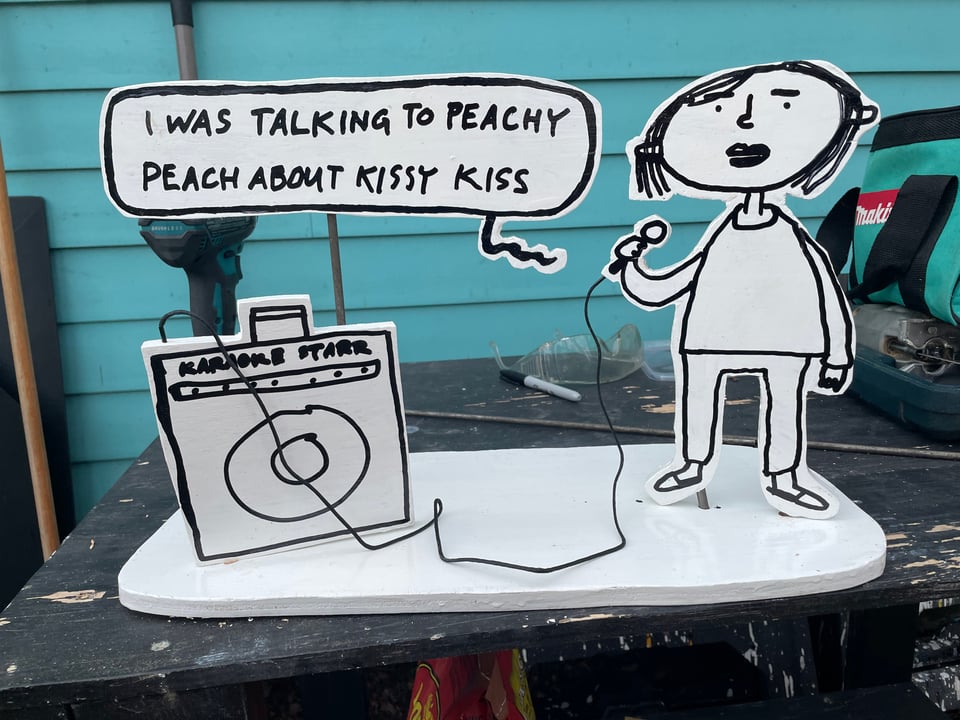 diorama or sculpture of woman singing I was talking to peachy peach about kissy kiss in a karaoke machine
